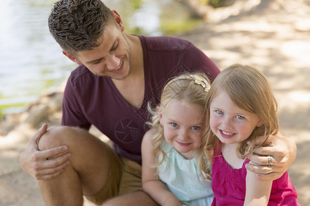 父亲和两个女儿在河岸上 图片