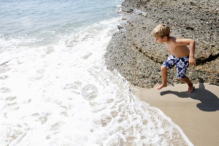 在岸边玩耍的男孩岩石高清图片素材