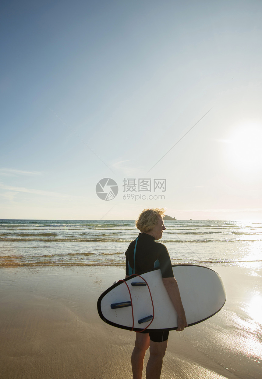 女冲浪运动员拿着冲浪板站在法国布列塔尼滨海海滩上图片