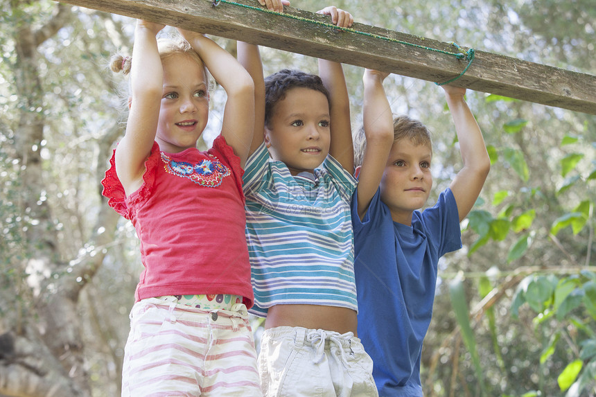 三个儿童把手放在栅栏上向远望去图片