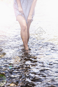 年轻女子抓着上衣走在浅水区图片