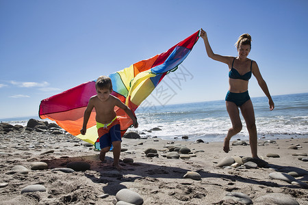 美州加利福尼亚洛杉矶县公园海滩上带多色纺织品的成人和儿子跑赤脚的高清图片素材