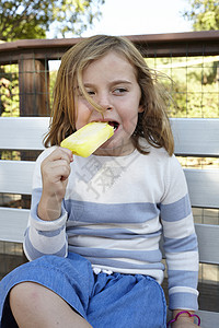 女孩在花园长椅上吃冰棒图片