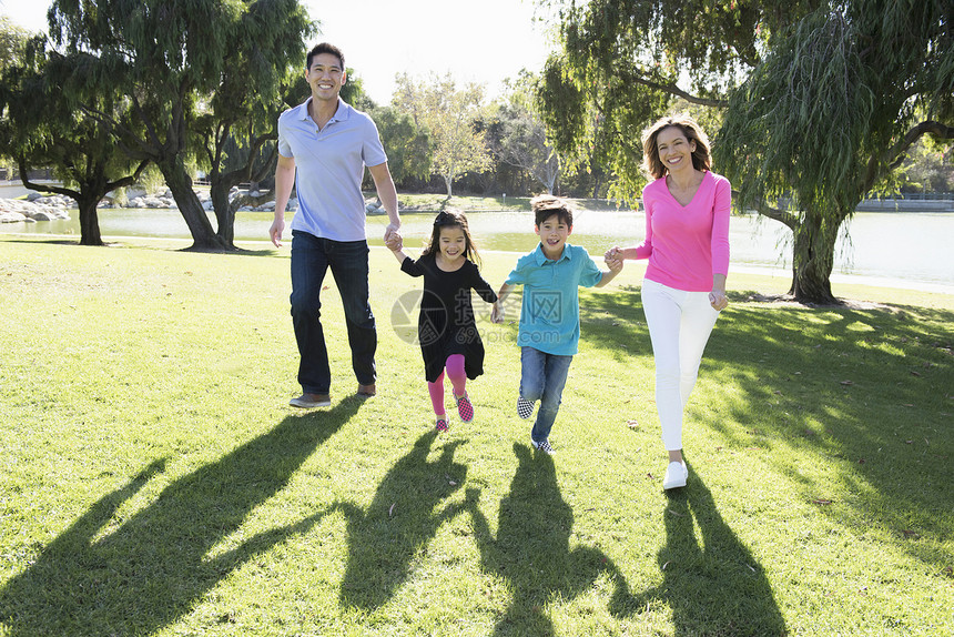 成熟夫妇和两个孩子在公园手牵手跑步图片