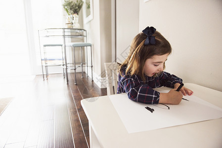 在桌上用蜡笔涂鸦的女孩图片