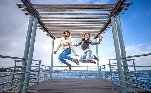 两个年轻女人一起跳上码头图片
