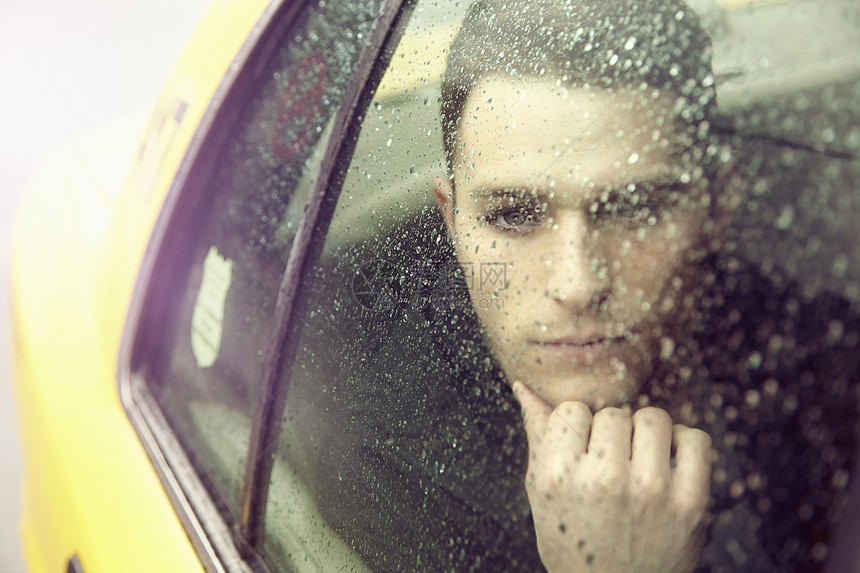 年轻人在出租车内看窗外的雨图片