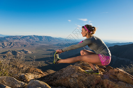 美国加利福尼亚州松树谷太平洋冠步道年轻女跑步者蹲着触摸脚趾图片
