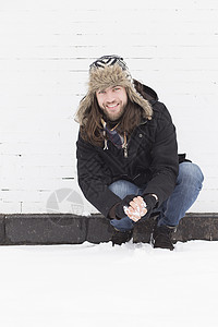 年轻人蹲着被雪覆盖的街头捏雪球图片