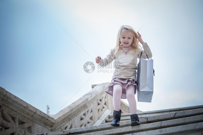 年轻女孩带着购物袋跑下楼梯图片