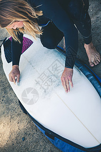 年轻女性在冲浪板上打蜡背景图片