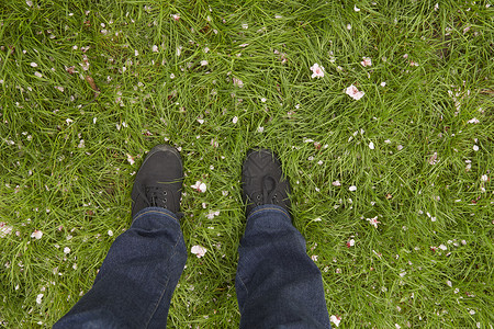 年轻女人看着踩在草坪上的双脚图片