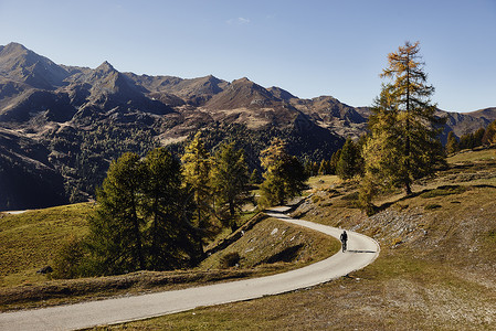 远山区公路上骑山地自行车的骑行者背景图片