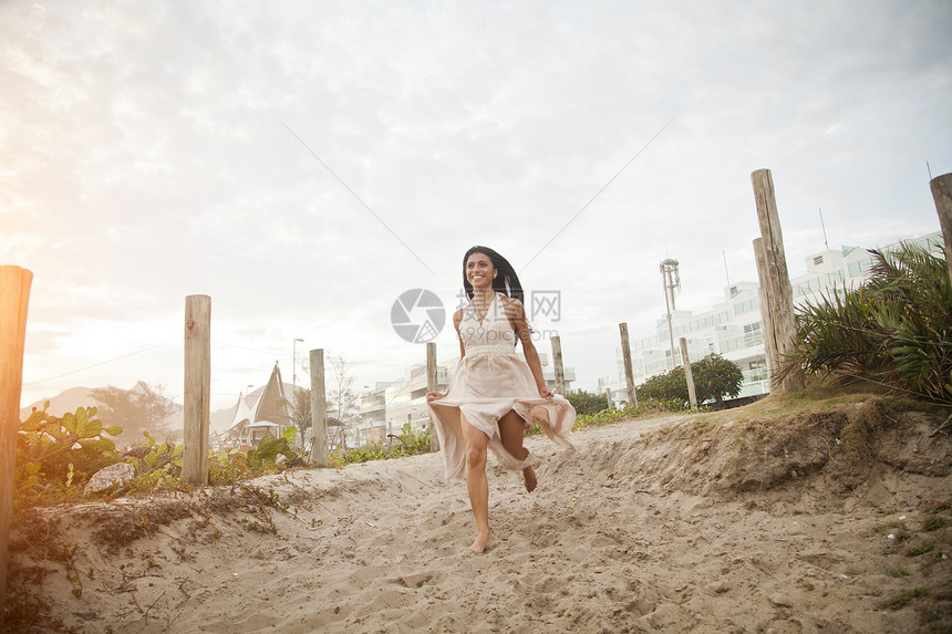 成年中妇女沿着沙道向海滩跑去图片