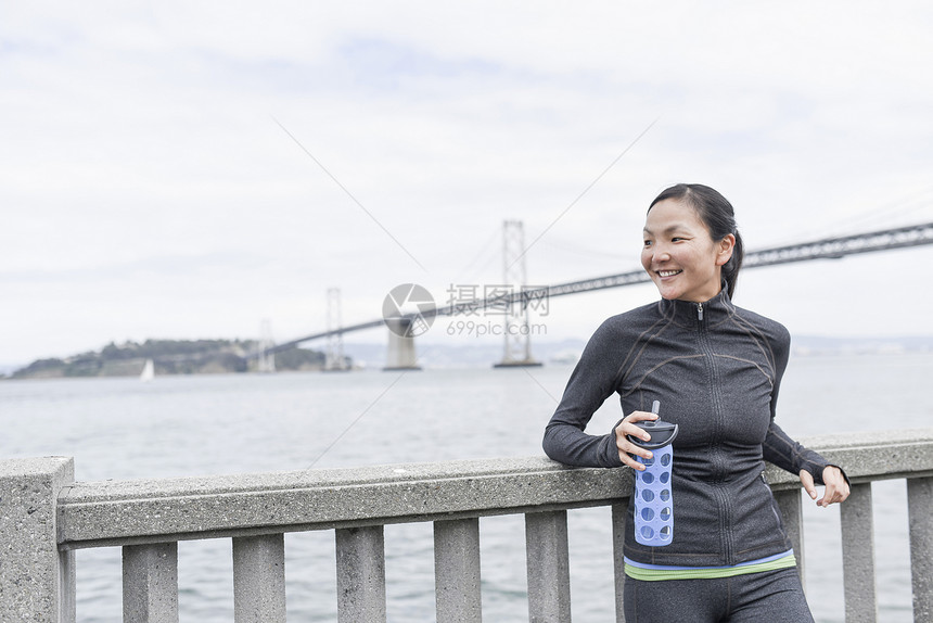 女子跑步运动员靠在护栏休息图片