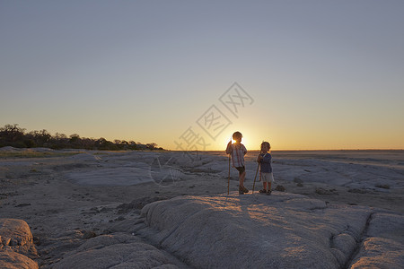 两名男孩站在岩石上拿着长矛高清图片
