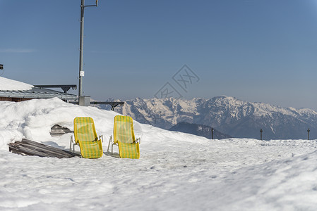 奥地利巴德伊施尔雪山上两个黄色躺椅高清图片