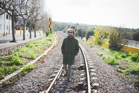 身戴太阳眼镜的中年成人在铁路上漫步图片