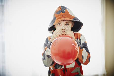 年轻男孩吹红气球背景图片