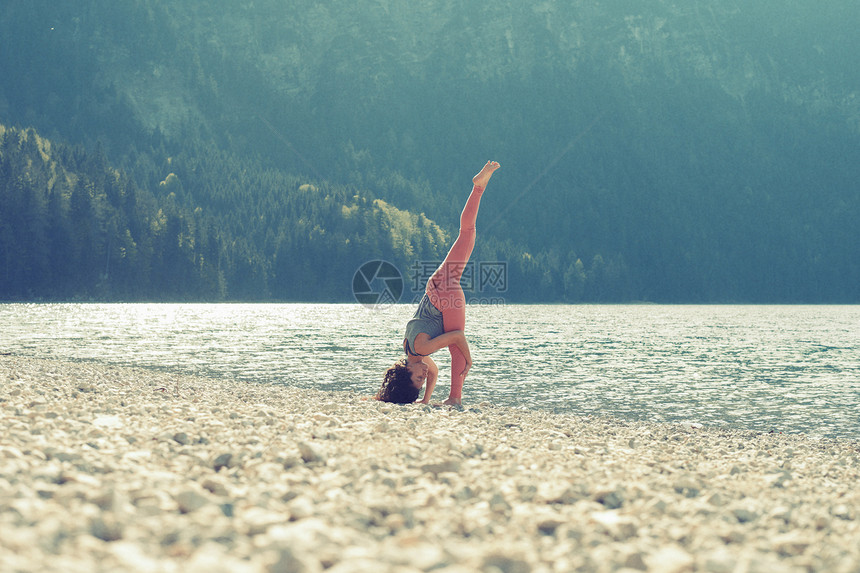 湖边坐瑜伽的年轻女性图片