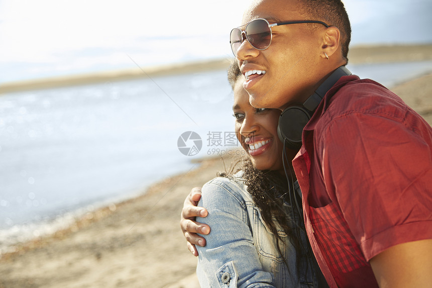 年轻夫妇在海滩上拥抱着向远看图片