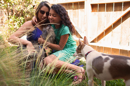 在花园里喂养狗的女孩和母亲忠诚高清图片素材
