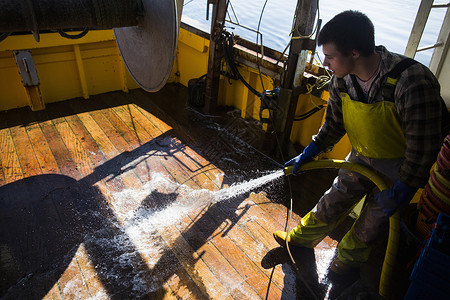 渔民冲洗拖网船底板图片