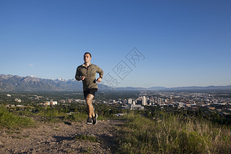 年轻男跑步者在山谷城市上空的赛道奔跑图片