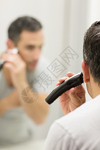 使用剃须刀刮胡子的男性图片