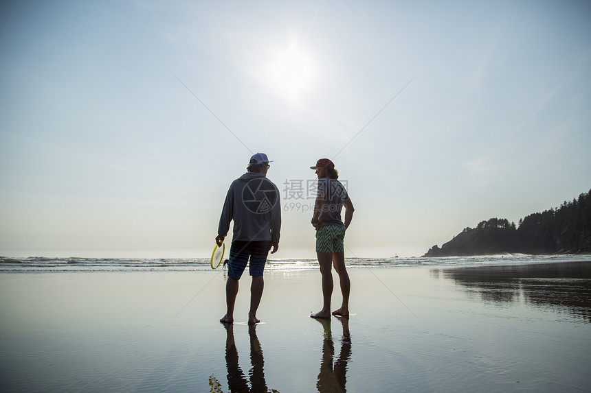美国俄勒冈州短沙滩上两位年轻人聊天背影图片