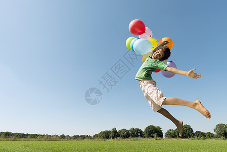 男孩拿着气球在草坪上起跳图片