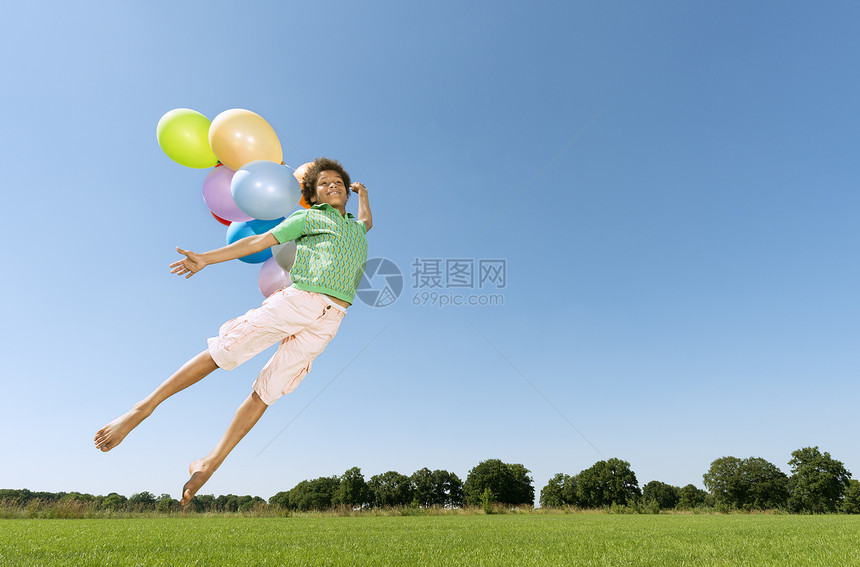 男孩拿着气球在草坪上起跳图片