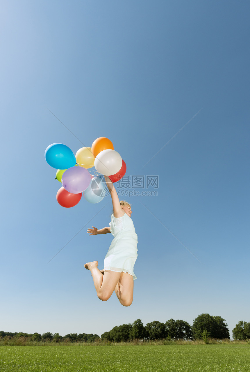 女孩拿着气球在草坪上起跳图片
