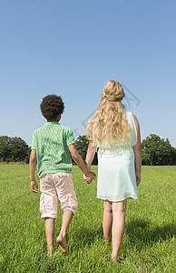 男孩和女孩牵着手在草地上走图片
