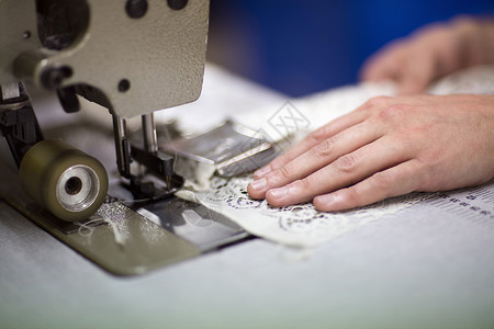在旧纺织厂使用缝纫机的男设计师的手图片
