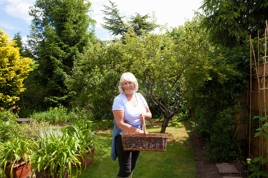 站在花园里拿着篮子的高龄妇女图片