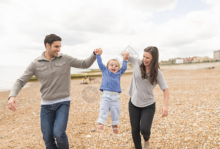 年轻家庭在石子海滩上手牵行走图片