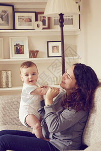 母亲和婴儿男孩在起居室玩两代人家庭高清图片素材