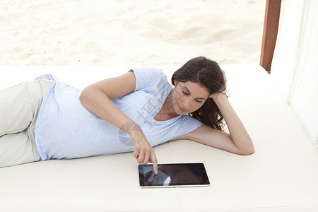 在沙发上躺着玩平板的孕妇图片