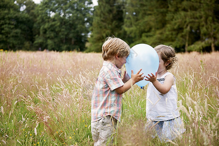 草地上玩气球的兄妹图片