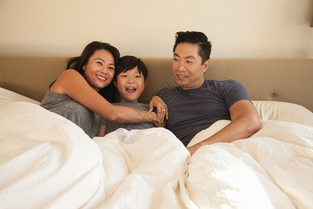 成年父母和儿子躺在床上可爱的高清图片素材