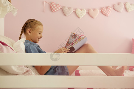 坐在床上阅读杂志的女孩背景图片
