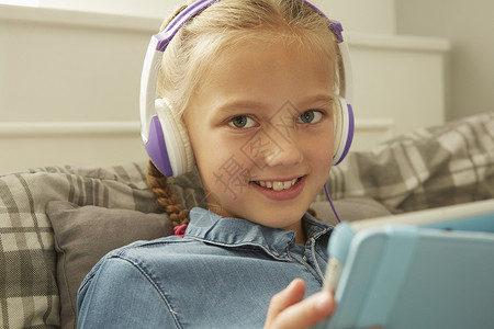 女孩戴数字平板电脑的耳机看着镜头微笑的图片