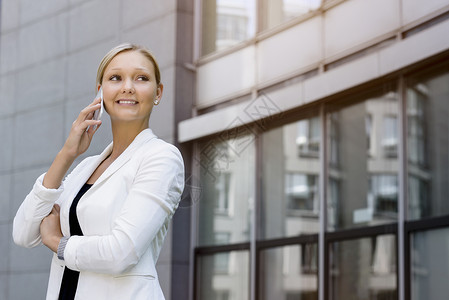在办公室外使用智能手机聊天的青年女性图片
