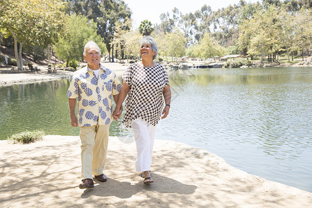 年长夫妇在湖边手牵行走水高清图片素材
