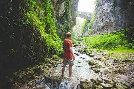 意大利加尔达背景中站在溪流岩山和石桥上的人图片
