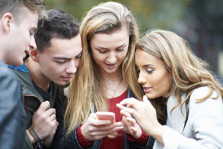 在户外看智能手机的青年成人群体背景图片
