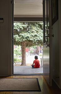 坐在房门口的年轻男孩背景图片