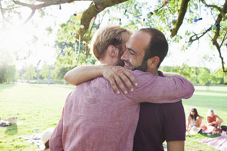 两个年轻人在公园的派对上互相拥抱政党高清图片素材