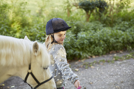 农村公路上领导白色小马的女童温顺的高清图片素材